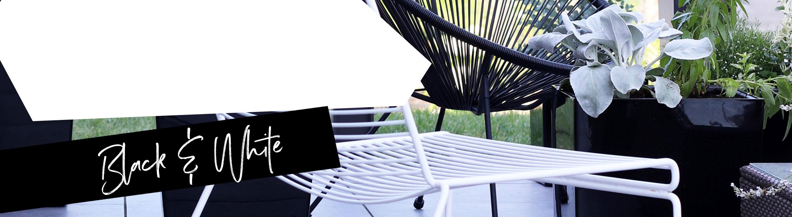 Черное блестящее кашпо на террасе со стальной садовой мебелью.