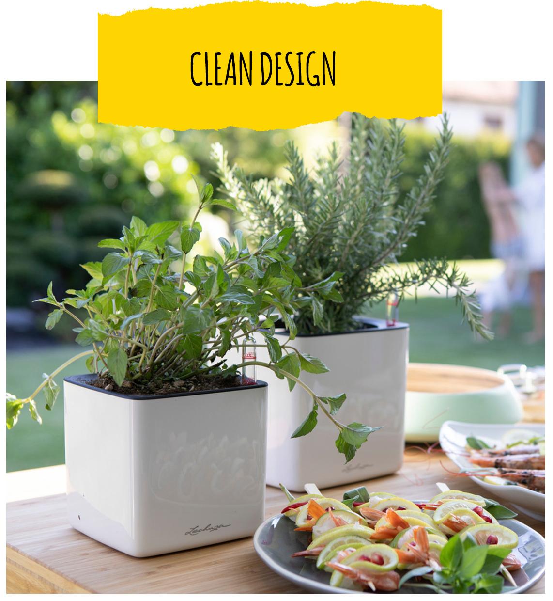 Two LECHUZA CUBE Glossy in white stand in the outdoor kitchen. They’re planted with various herbs.