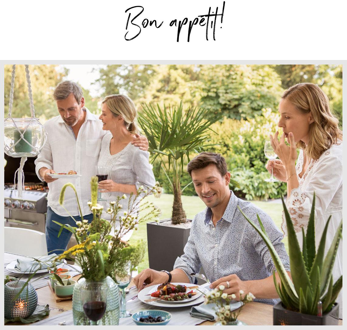 Four friends sit down to dinner at a beautifully laid table outdoors.