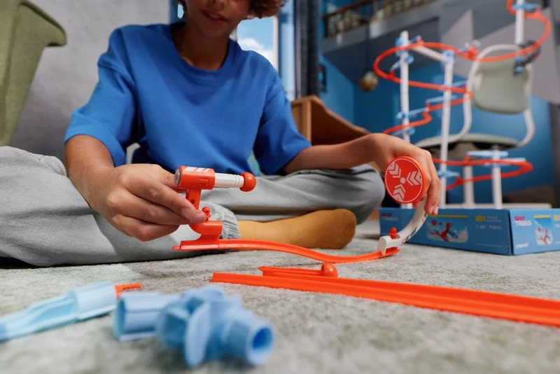 Barn bygger ihop Track Blaster-avfyrningsmodulen på mattan – kreativt SKY TRAILS-byggset för barn från 7 år.