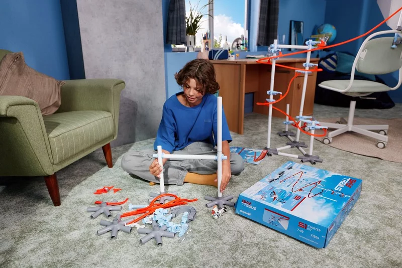 Boy sitting in playroom building a complex space-themed SKY TRAILS track with the Construction Pack - exciting building set for kids aged 7 and up