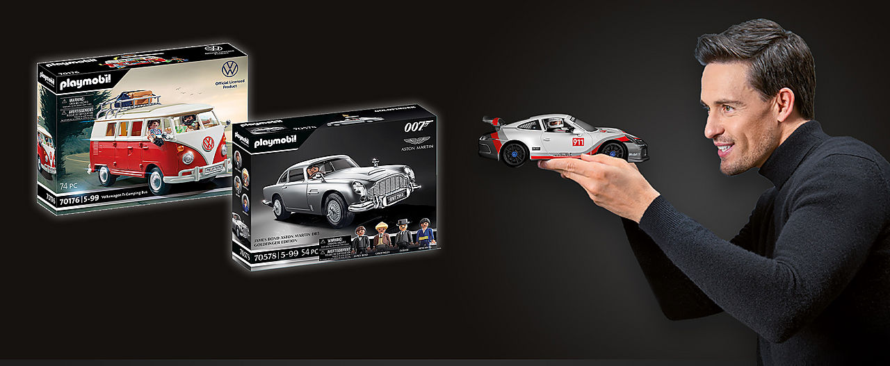 shows a man holding the car 70764 Porsche 911 GT3 Cup in his hand and looking at it - The two products 70826 Volkswagen T1 Camping Bus - Special Edition and 70578 James Bond Aston Martin DB5 - Goldfinger Edition are shown in the package