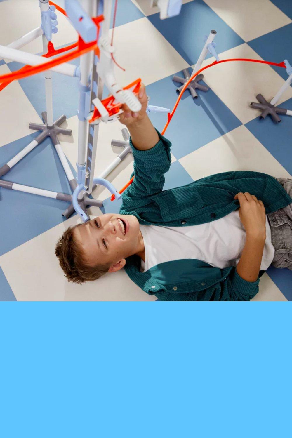 Junge spielt mit PLAYMOBIL&reg; Sky Trails auf dem Boden liegend &ndash; spannender Spielspa&szlig; mit Loopings und Geschwindigkeit.