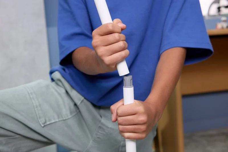 Child assembling a white plastic rod, wearing blue t-shirt - Playmobil SKY TRAILS set in use