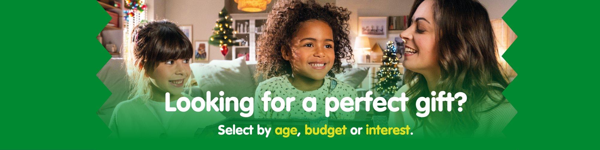 Two children and a woman smiling together in a cozy living room decorated for Christmas &ndash; discover perfect gift ideas for kids.