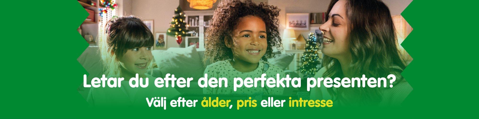 Tv&aring; barn och en kvinna ler i ett vardagsrum dekorerat f&ouml;r julen &ndash; uppt&auml;ck perfekta julklappstips f&ouml;r barn.
