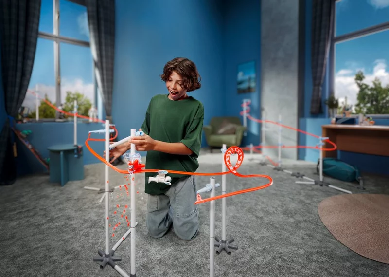 Junge kniet begeistert vor einer Sky Trails Bahn, die mit Schleifen und Loopings im Kinderzimmer aufgebaut ist