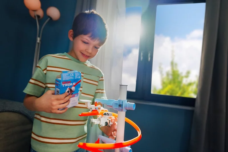 Junge spielt mit dem SKY TRAILS Starter Kit und hält die Verpackung in der Hand ? kreatives Konstruktionsspielzeug für Kinder ab 7 Jahren.