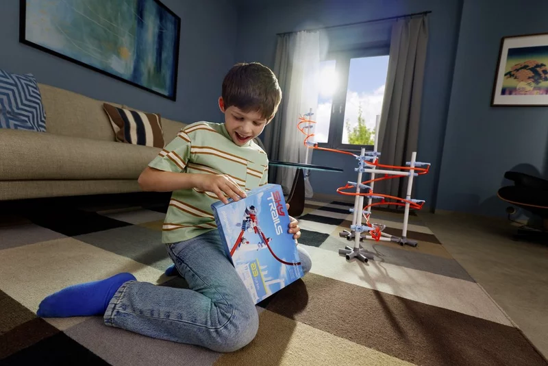 Junge sitzt auf dem Wohnzimmerteppich und öffnet begeistert eine SKY TRAILS Box von Playmobil.